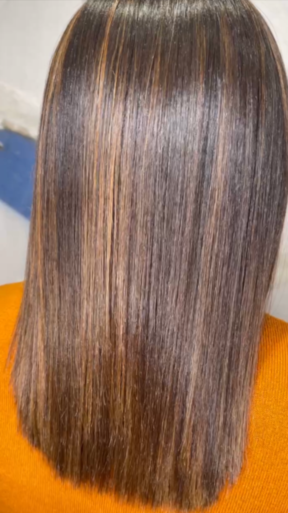 a picture of brown hair with golden highlights that has had a fabriq treatment. it is very smooth, shiny and glossy